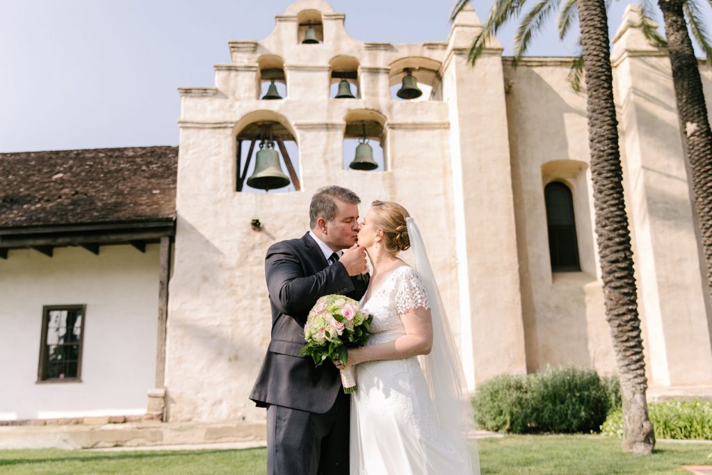 bride and groom under the mission bells 