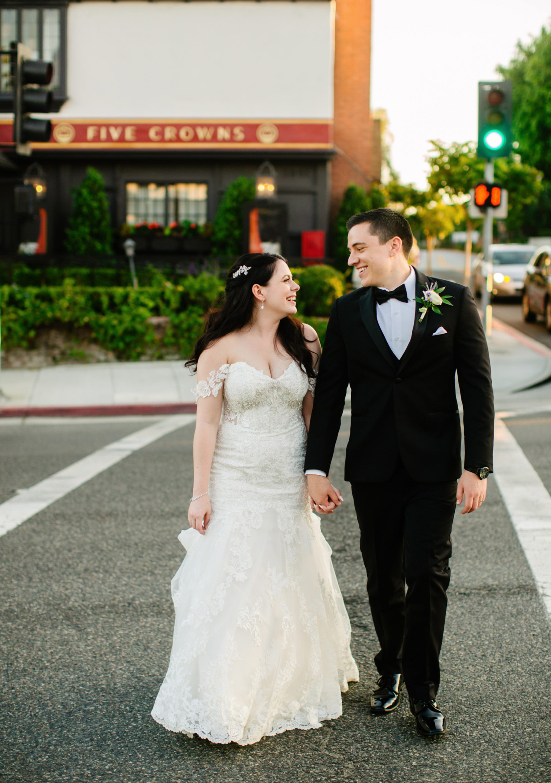 Bride and groom smiling at each other while crossing the street near Five Crowns in Corona del Mar, taken by Christopher Brown