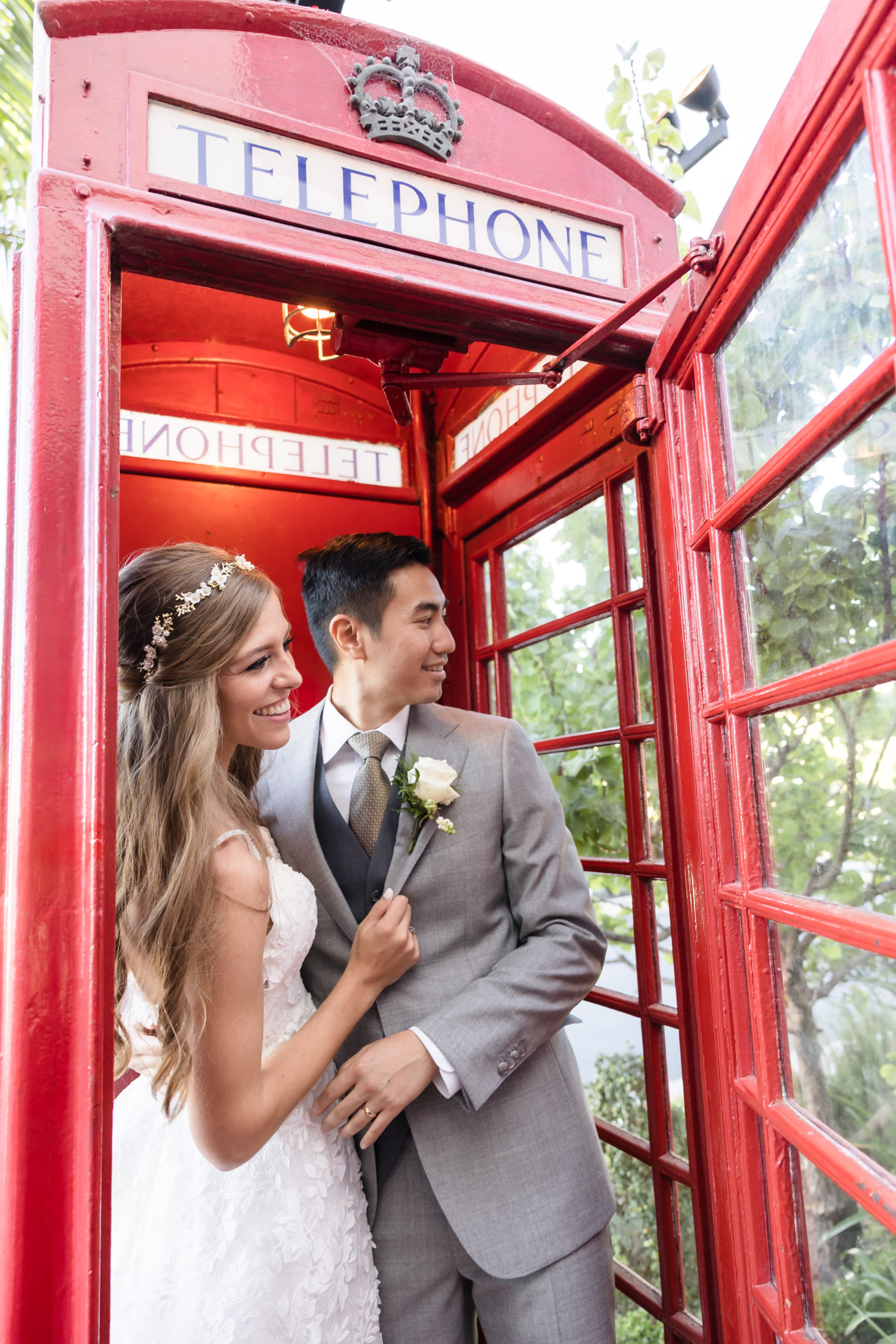 Bride and groom posing inside red telephone booth, captured by Christopher Brown Weddings