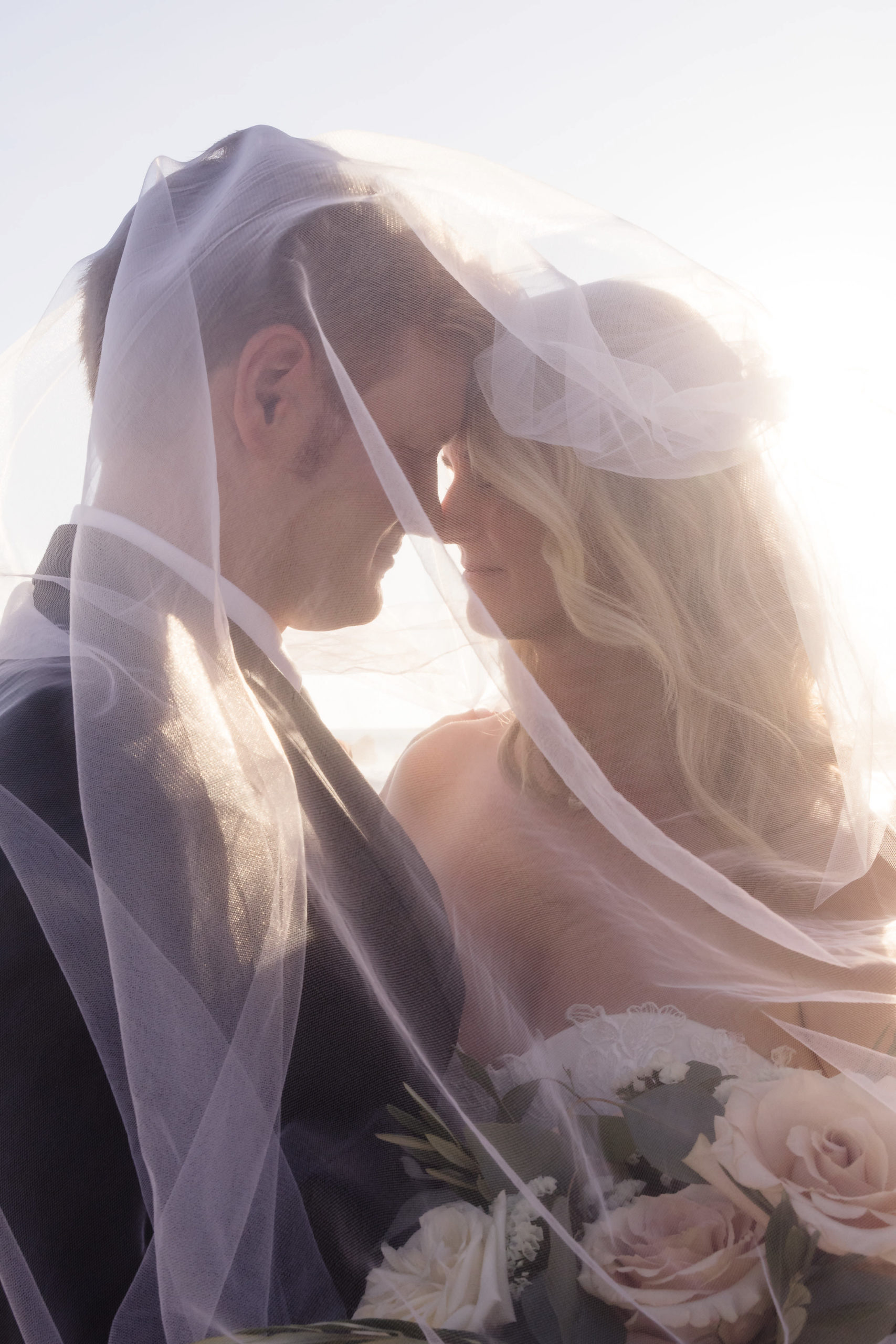 Close-up shot of bride and groom under sheer veil, shot by natural light photographer Christopher Brown