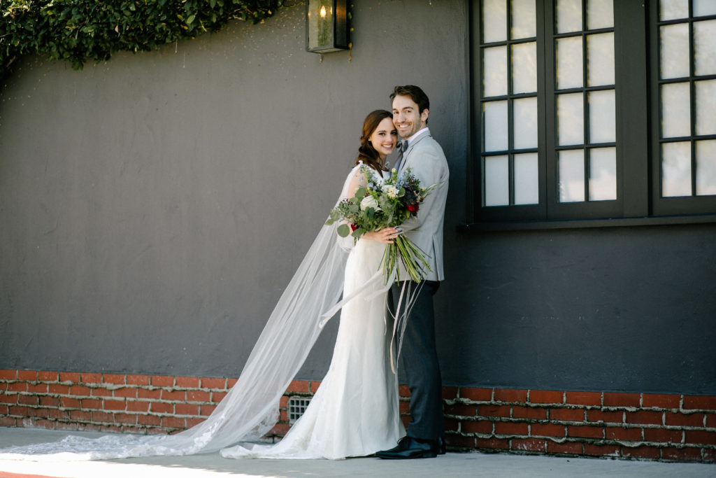 Bride and groom posing next to grey wall at Five Crowns in Corona del Mar, taken by Christopher Brown Weddings