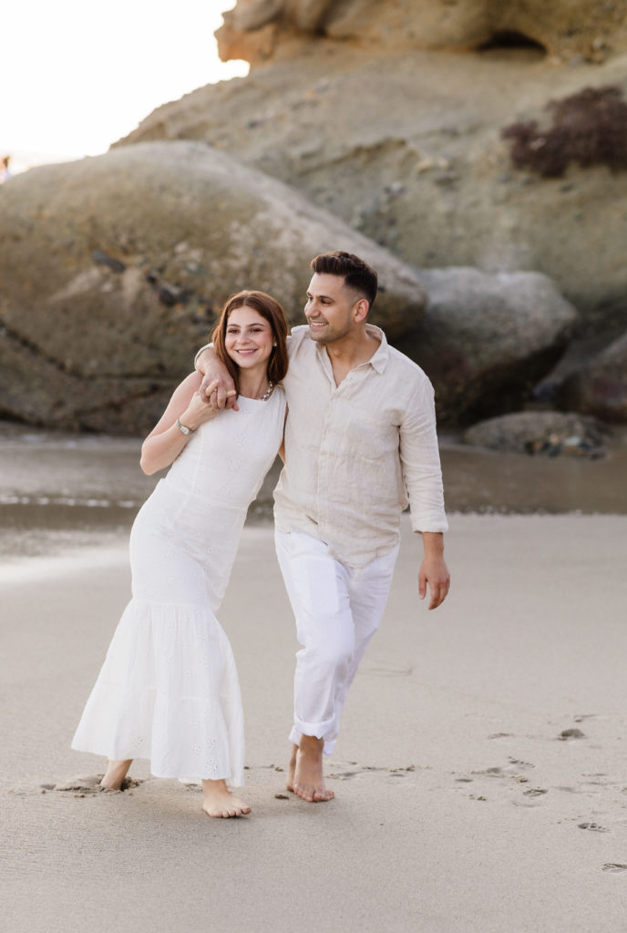Bride and groom smiling as they walk along Shaw's Cove, one of the top 6 Laguna Beach engagement photo locations