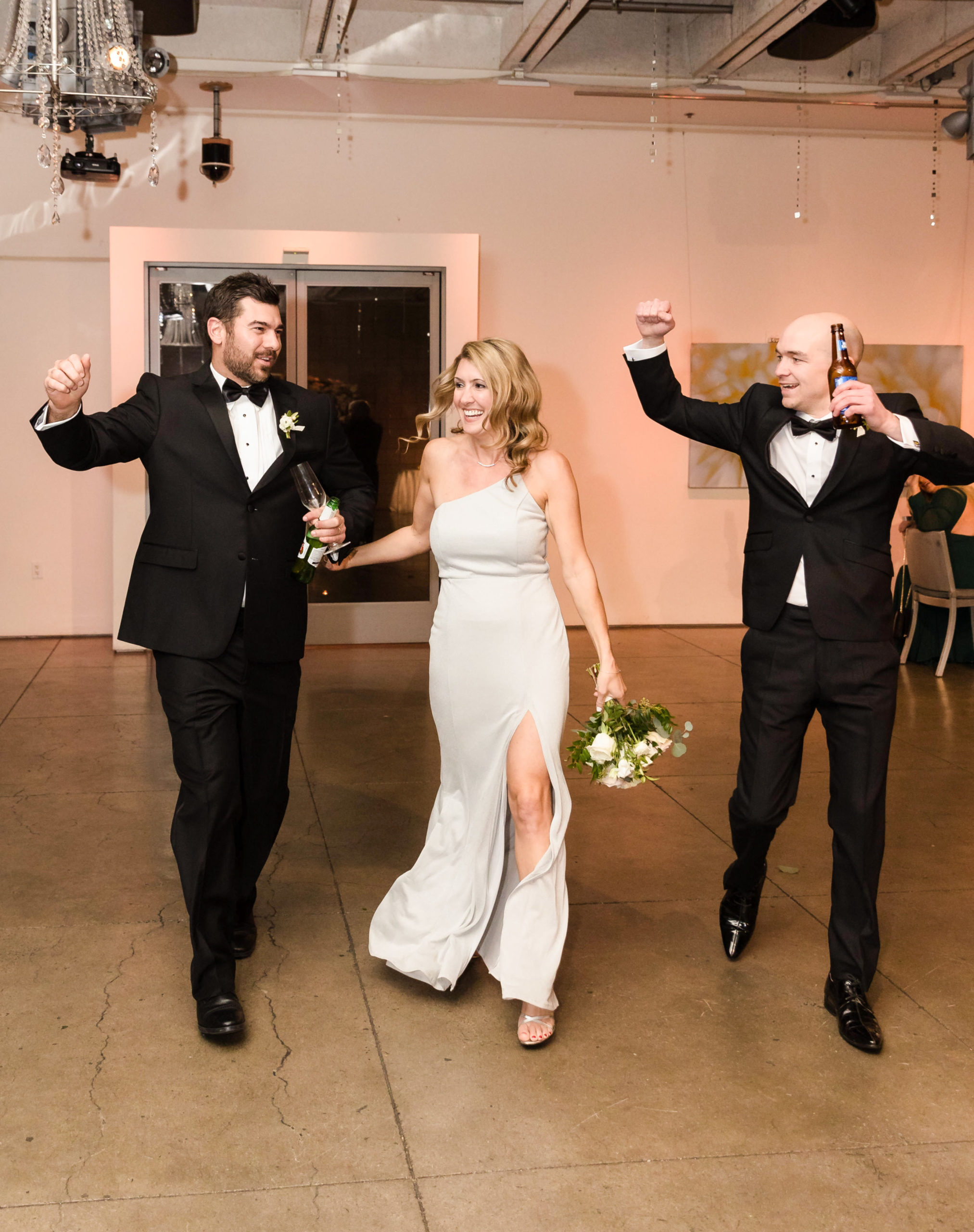 Bridesmaid and two groomsmen walking excitedly into reception hall, shot by modern wedding photographer Christopher Brown
