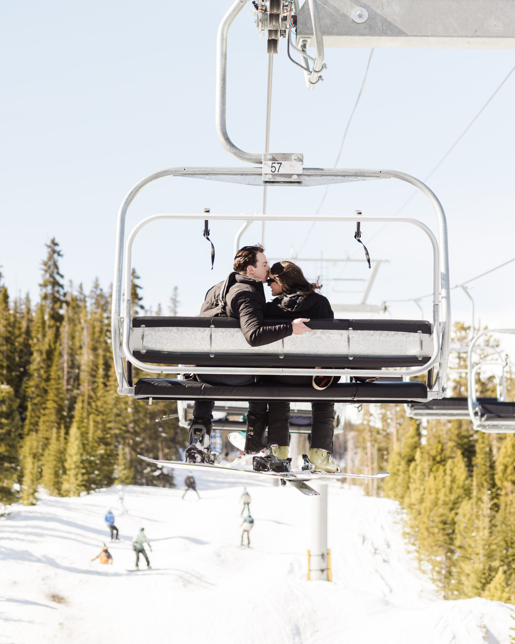 Couple on a ski lift with guy kissing his bride on the forehead, captured by Christopher Brown Weddings