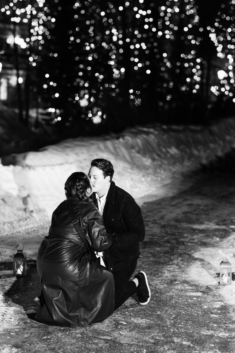 Black and white photo of couple kneeling and sharing a kiss in the middle of a path, taken by Southern California wedding photographer Christopher Brown