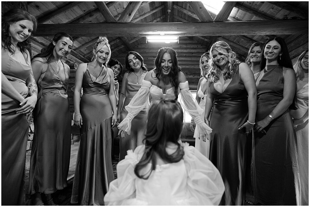 Bride and bridesmaids all looking down at little girl with bride's arms outstretched