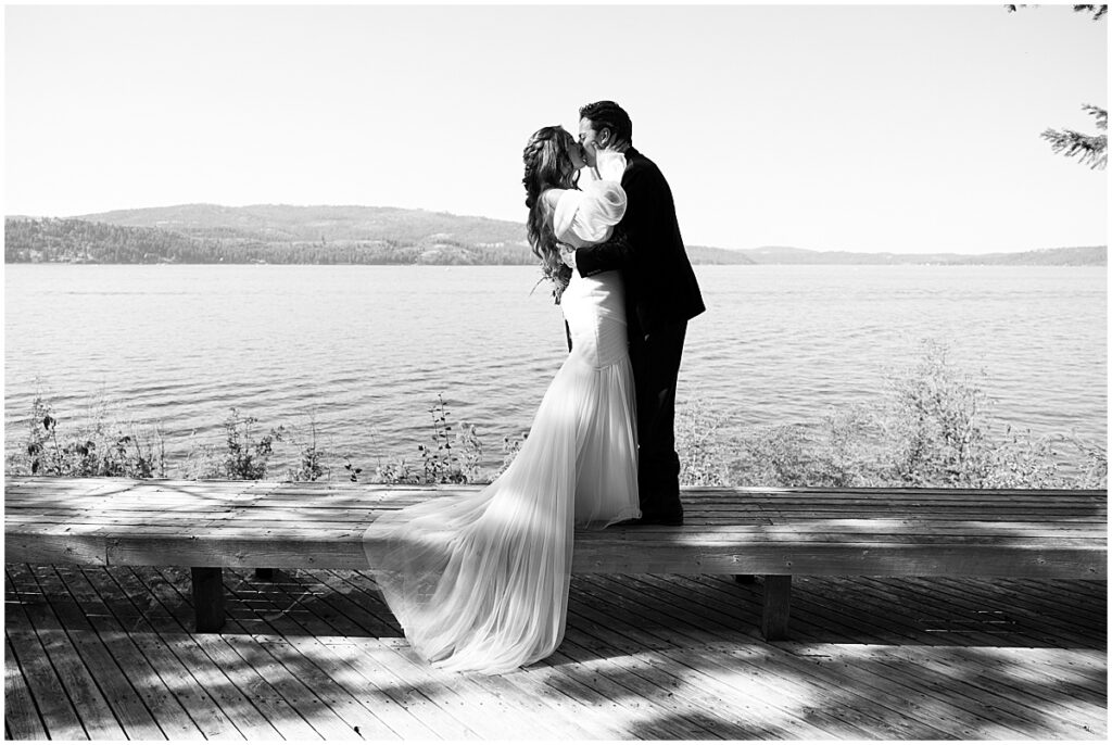 Bride and groom kissing in front of lake at Coeur d’Alene