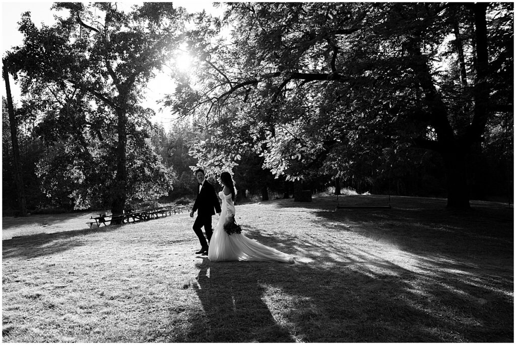 Bride and groom walking along under the trees at Coeur d’Alene