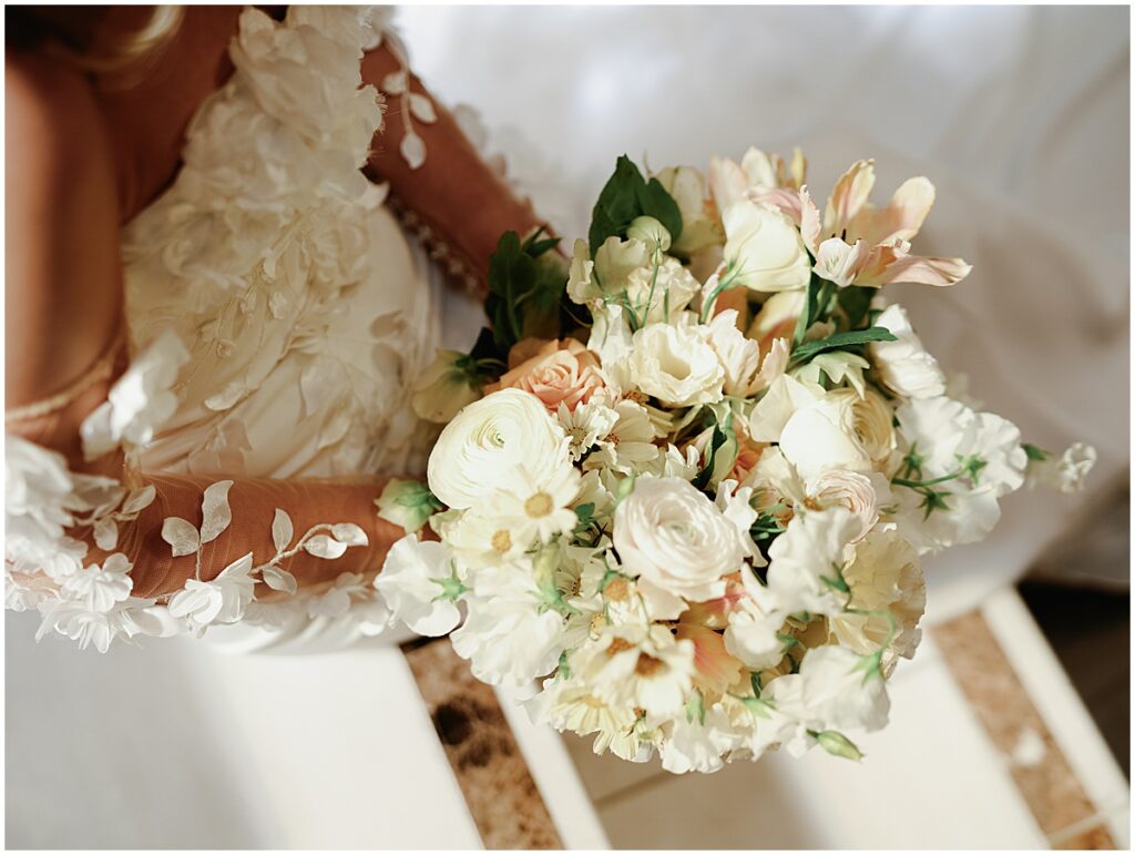 bride holding bouquet of ivory and peach colored florals