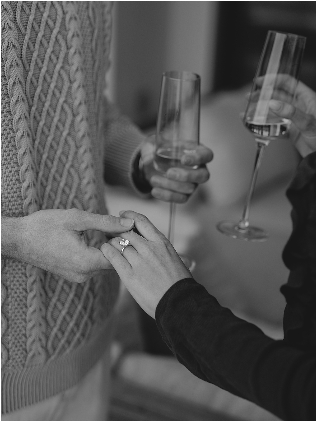 couple holding hands showing engagement ring, holding champagne flutes