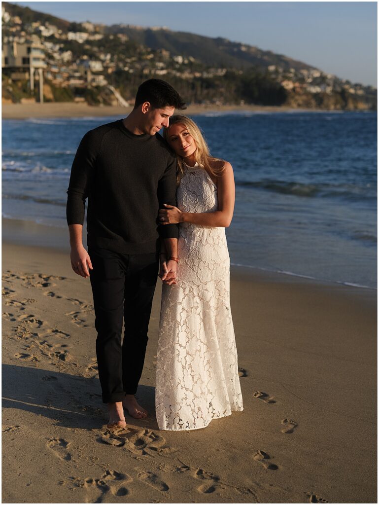 Couple walking along and kissing on beach at Treasure Island, Laguna Beach