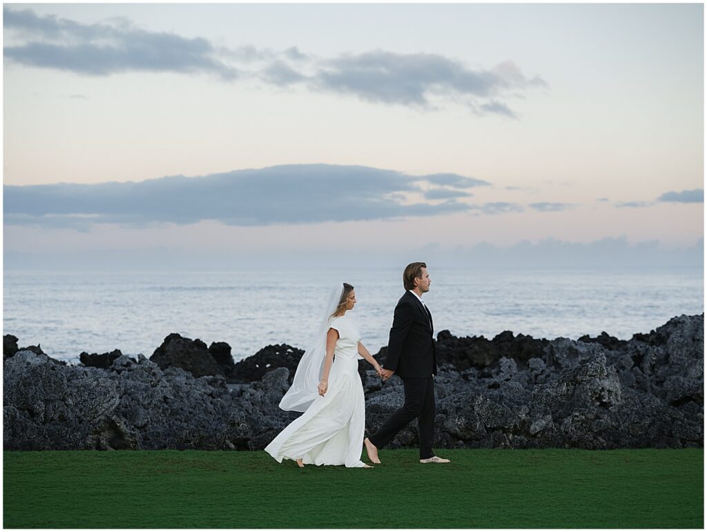 Bride and groom walking along by the ocean at Four Seasons Hualalai