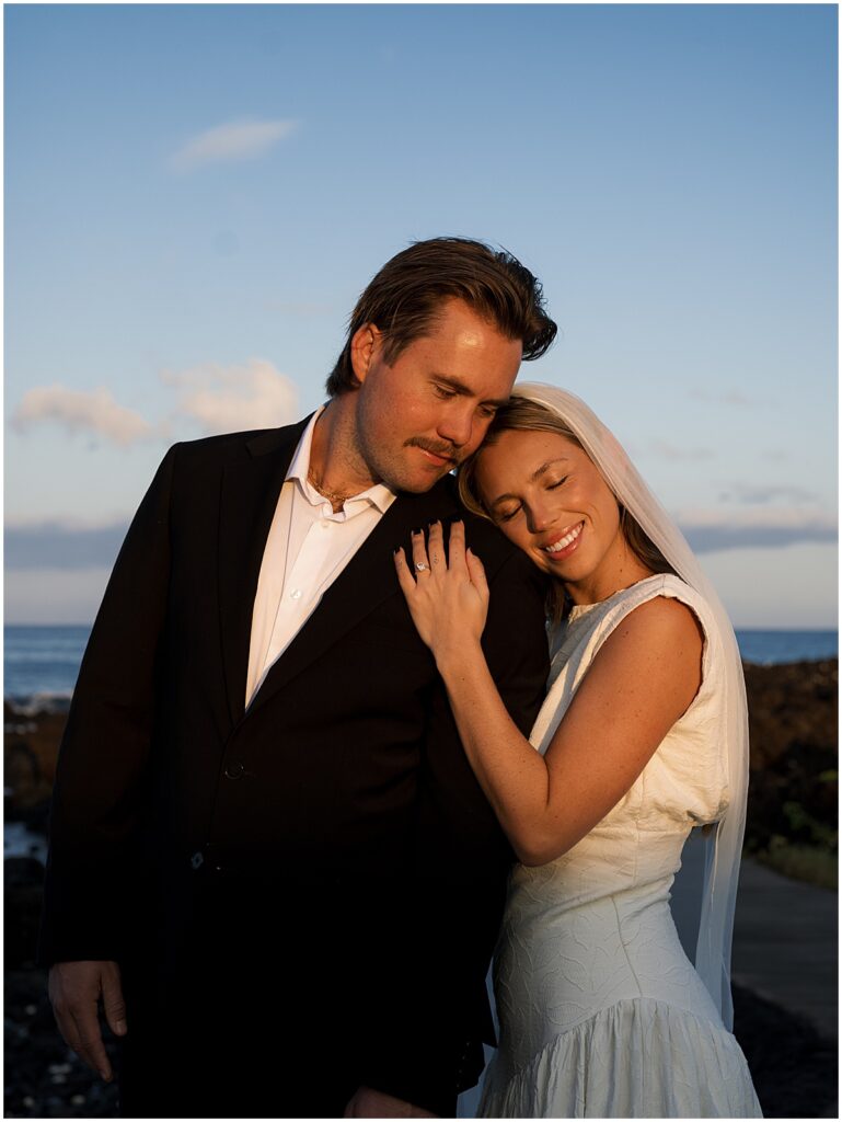 Bride resting head on grooms shoulder looking happy at Hawaii wedding