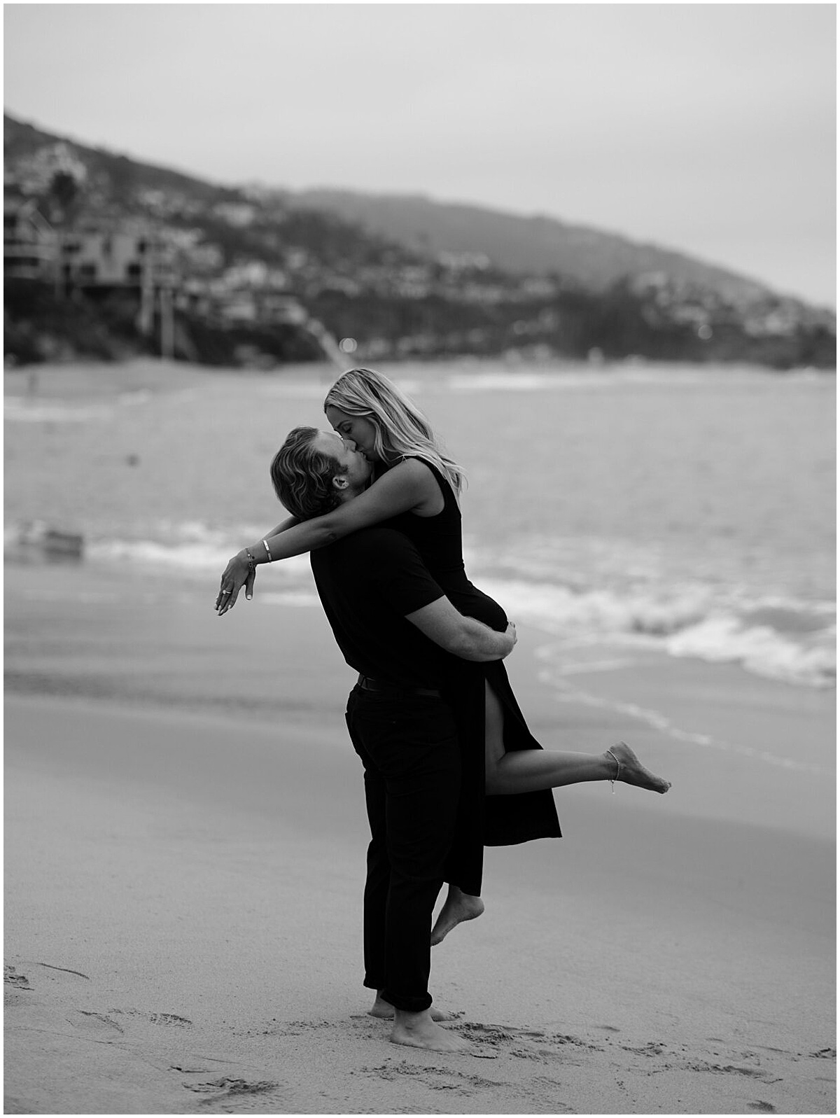 Man lifting woman up on beach at Laguna Beach engagement session