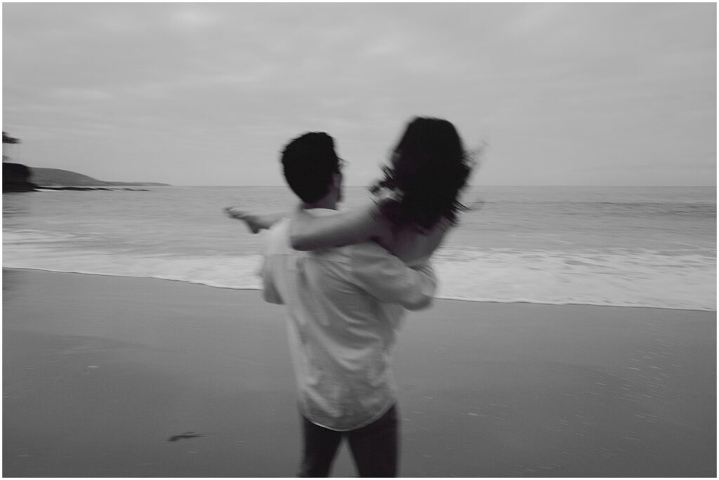 Couple taking sunrise engagement photos at the beach in Southern California